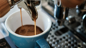 Espresso being extracted into a blue mug