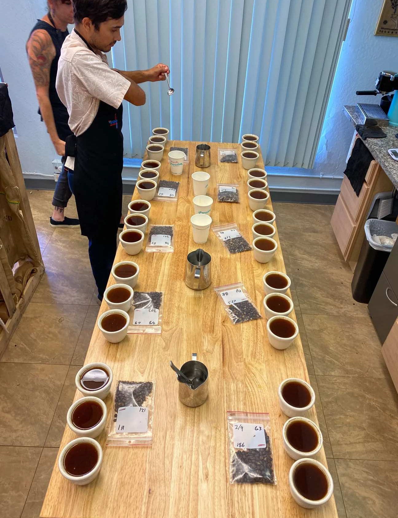 Coffee cupping table with Kona coffee samples being evaluated by tasters