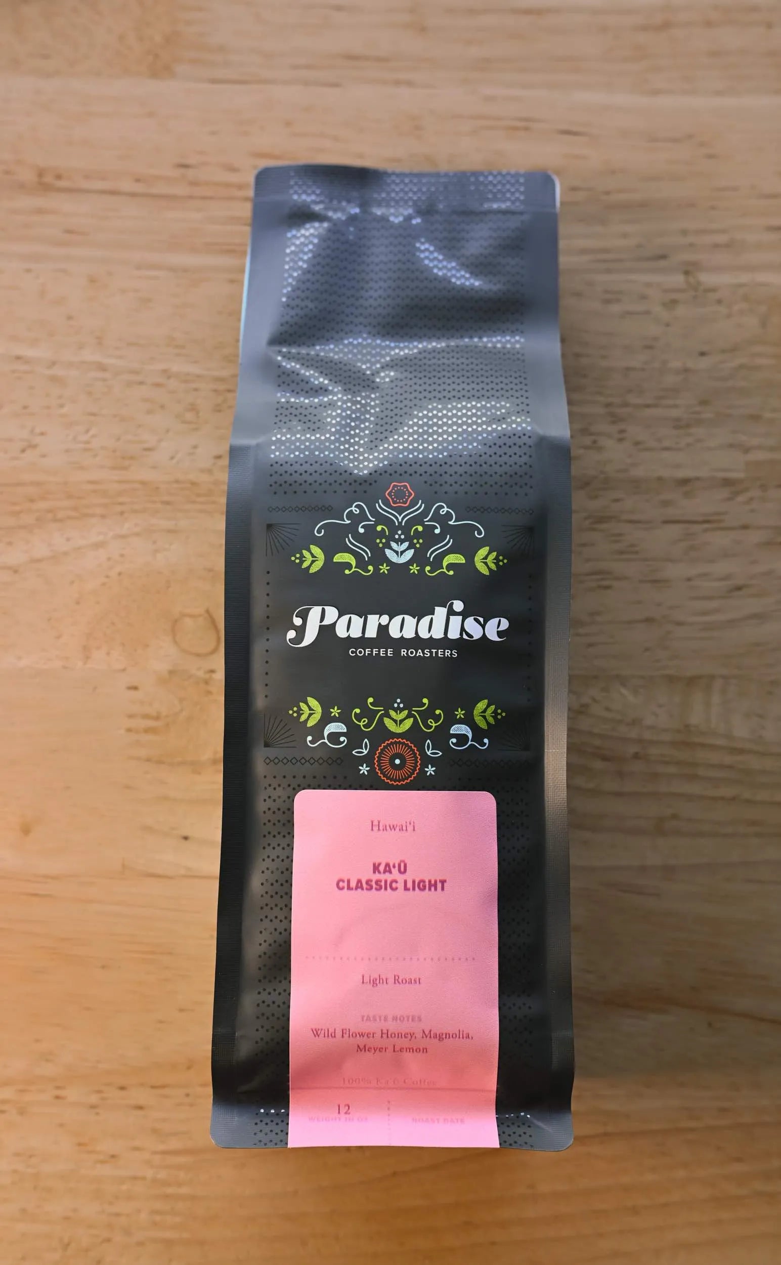 Paradise Roasters Kaʻu Classic Light coffee bag, 12oz, showing pink label with tasting notes Wildflower Honey, Magnolia, and Meyer Lemon